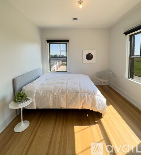 A bedroom with a bed, a small table, and a window overlooking a bridge.