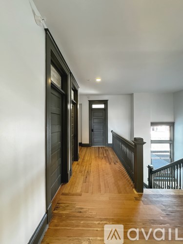 A hallway with a wooden floor and a black door.
