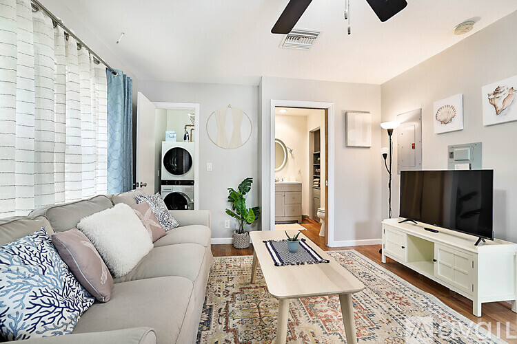 A living room with a couch, a coffee table, and a television.