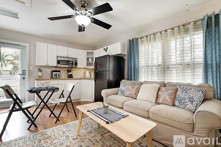 A living room with a couch, a dining table, and a ceiling fan.