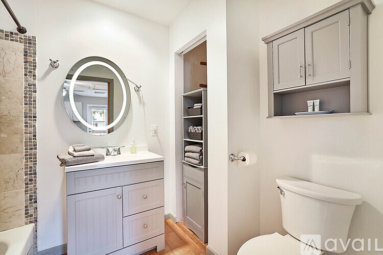 A bathroom with a white tub and a round mirror.
