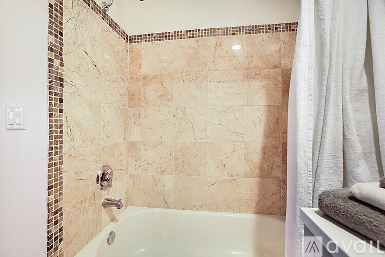 A bathroom with a tiled wall and a bathtub.