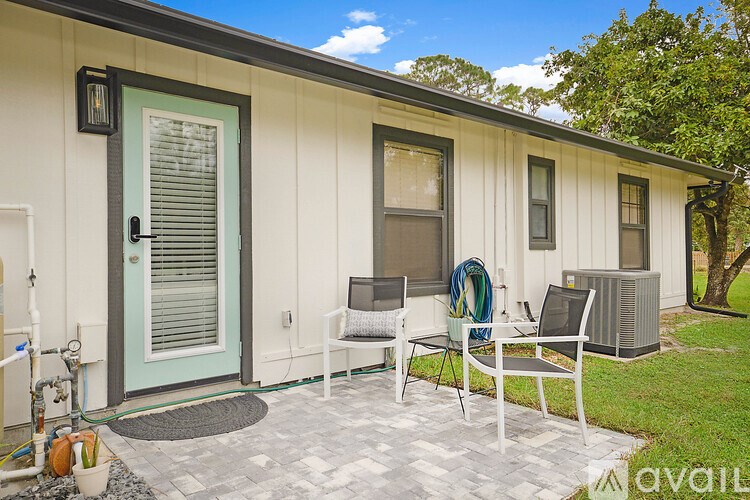 A small house with a blue door and a patio with chairs and a table.