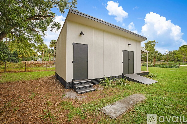 A small white building with a black door and a metal grate on the front.