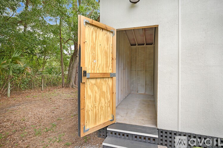 A wooden door is open to a room with a concrete wall.