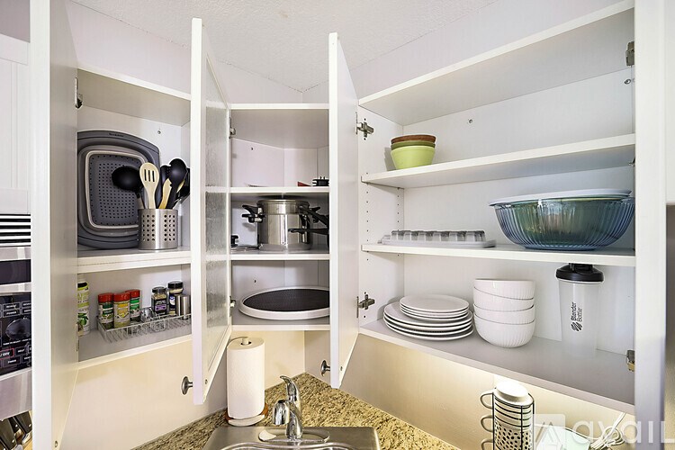 A kitchen with a sink and open cabinets.
