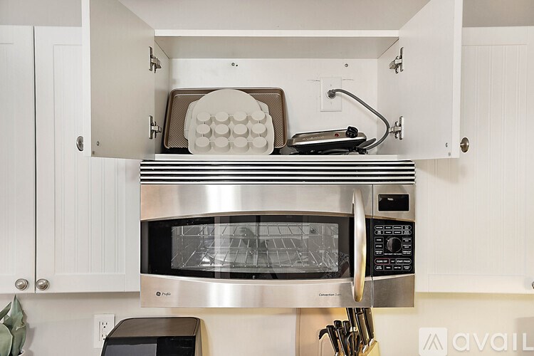 A silver microwave oven is on a white countertop.
