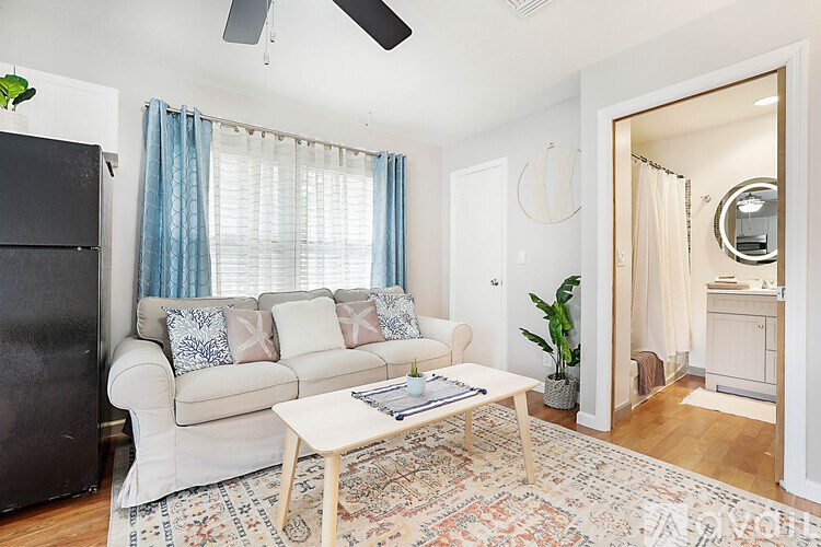 A living room with a white couch and a rug.