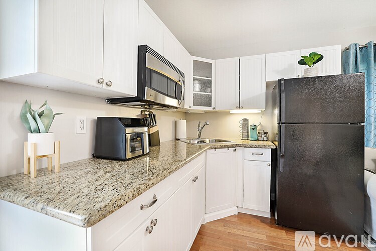 A kitchen with a black refrigerator and white cabinets.
