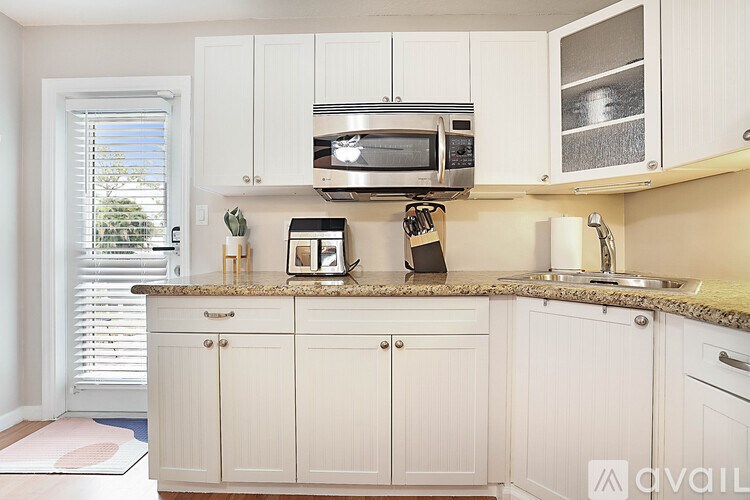 A kitchen with white cabinets and a granite countertop.