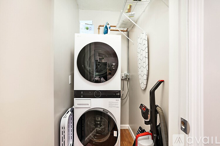 A white washing machine and dryer stacked on top of each other in a small laundry room.