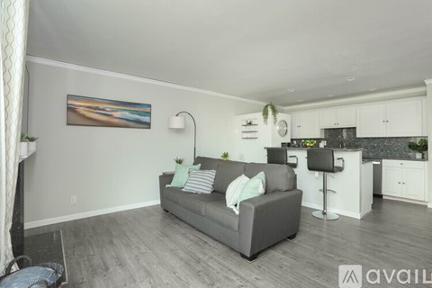 A living room with a grey couch and a painting on the wall.