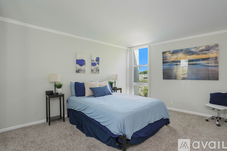 A bedroom with a bed, two lamps, and pictures on the wall.