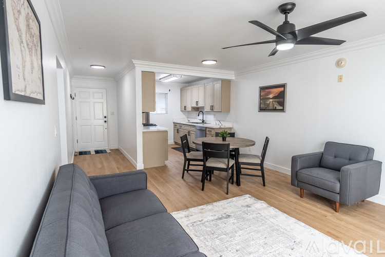 A living room with a grey couch and a dining table with chairs.