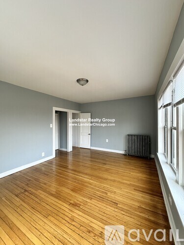 A room with wooden floors and a window on the right side.