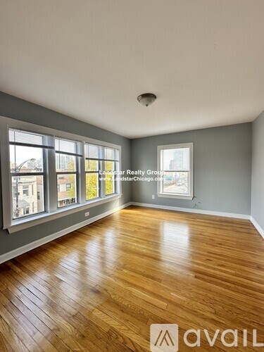 A room with wooden flooring and a large window overlooking a street.