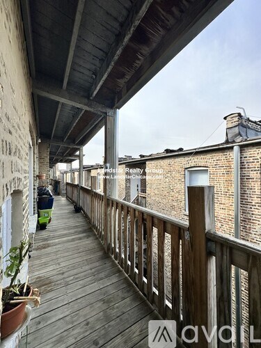 A wooden balcony with a railing and a few potted plants.