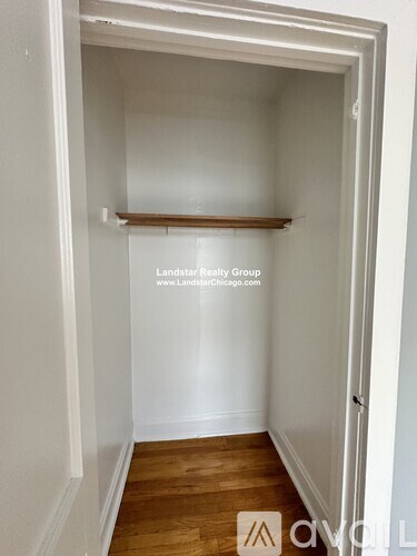 A white hallway with a wooden floor and a white door.
