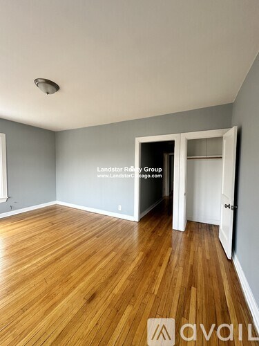 A room with wooden flooring and a doorway leading to another room.