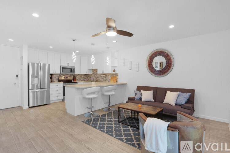 A modern kitchen with a refrigerator, stove, and a dining area with a couch and chairs.