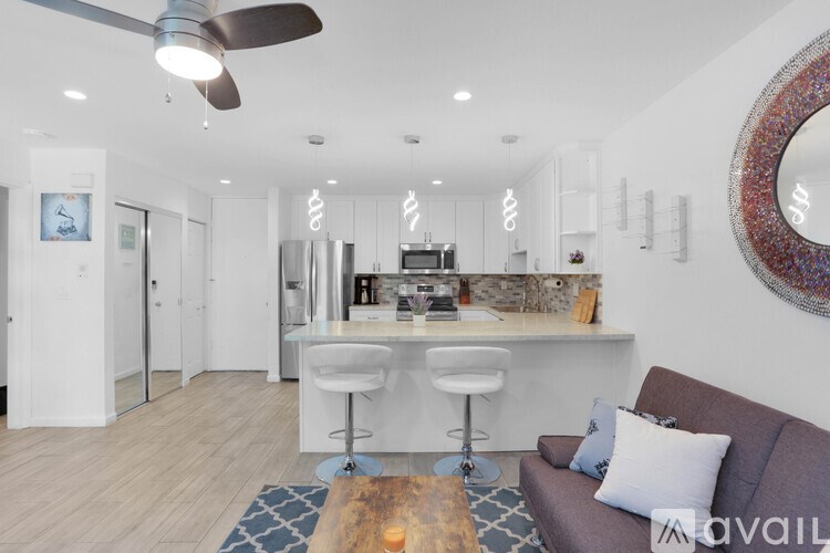 A modern living room with a bar area and a ceiling fan.
