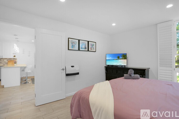 A bedroom with a bed, a TV, and a painting on the wall.