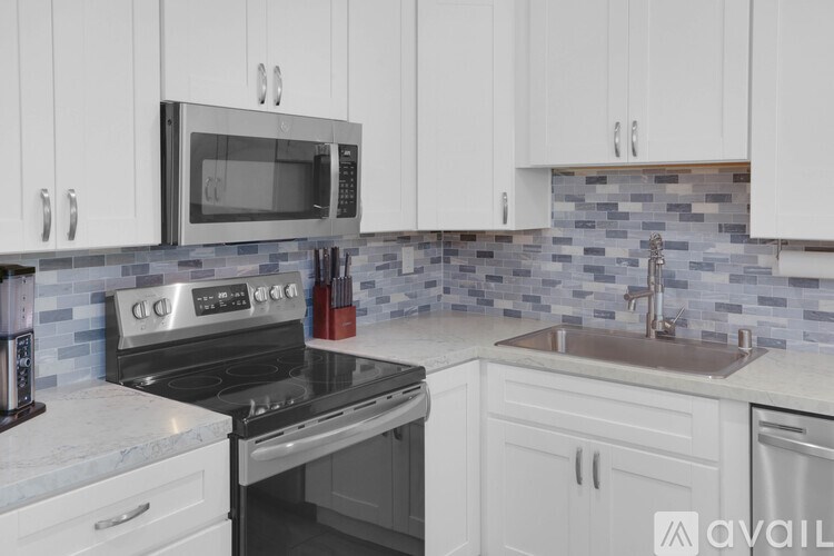 A kitchen with white cabinets and a black microwave above the stove.