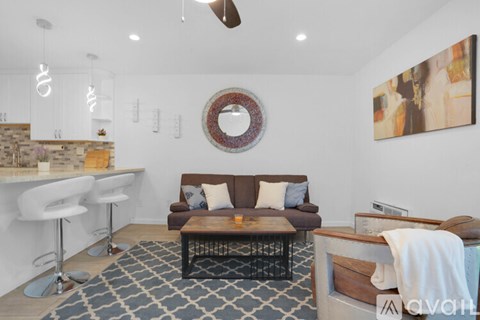 A living room with a brown couch and a round mirror on the wall.