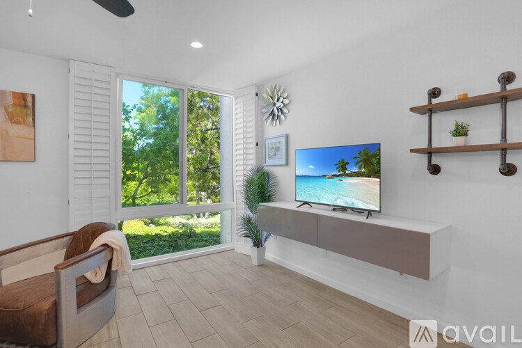 A living room with a television, a chair, and a window showing an outdoor view.