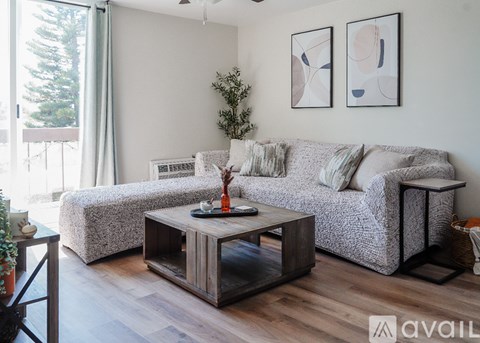 A living room with a grey couch, a wooden coffee table, and two abstract paintings on the wall.
