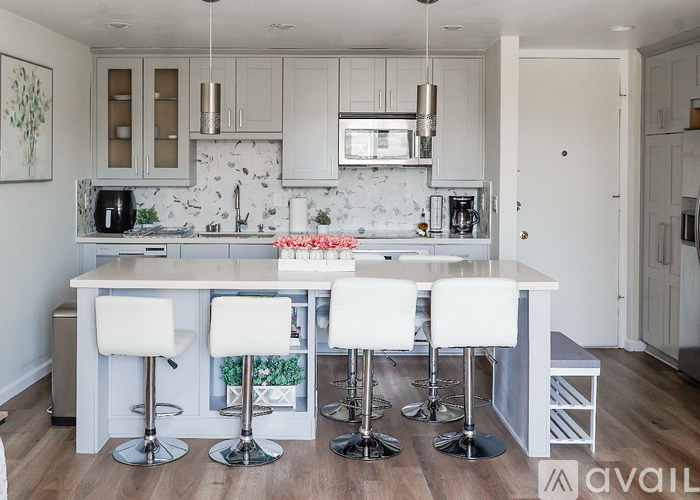 A kitchen with a white counter and bar stools.