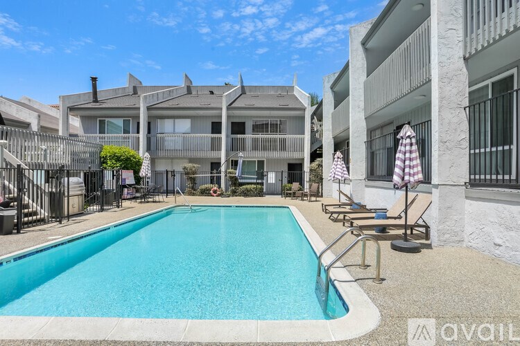 A swimming pool is surrounded by a concrete patio and a building.