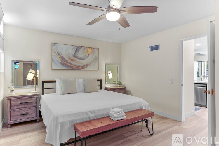 A bedroom with a bed, nightstand, and a painting on the wall.