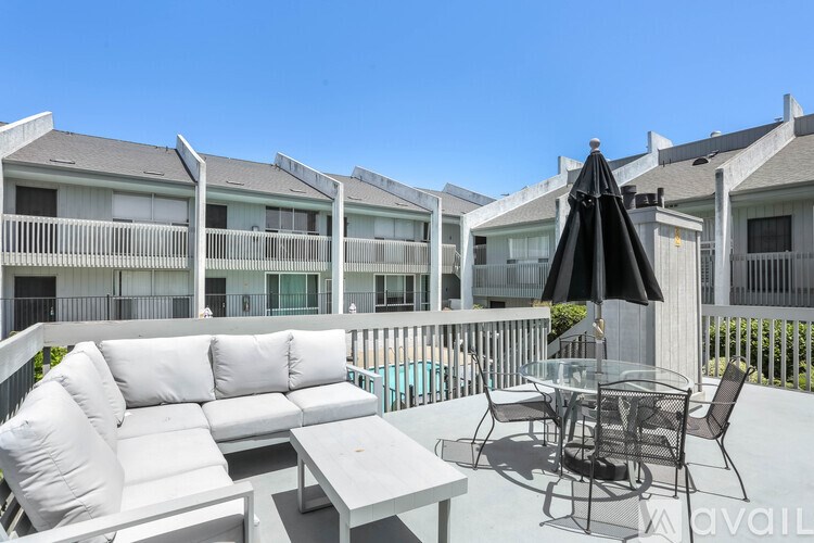 A patio with a table, chairs, and an umbrella is set up on a sunny day.