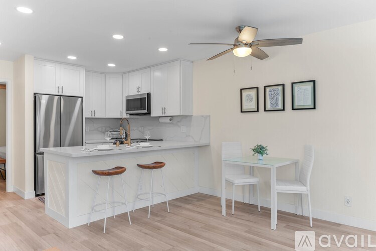 A kitchen with white cabinets and a bar area with stools.