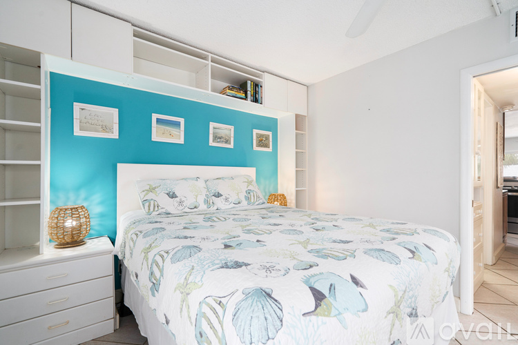 A bedroom with a bed, a dresser, and a wall with pictures.