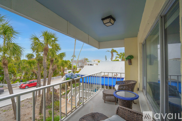 A balcony with a table and chairs overlooking a pool and trees.