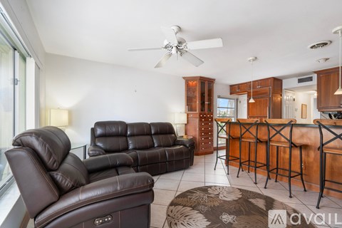 A living room with a black leather couch and a brown leather chair.