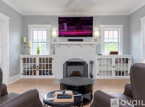 A living room with a fireplace and a television mounted above it.
