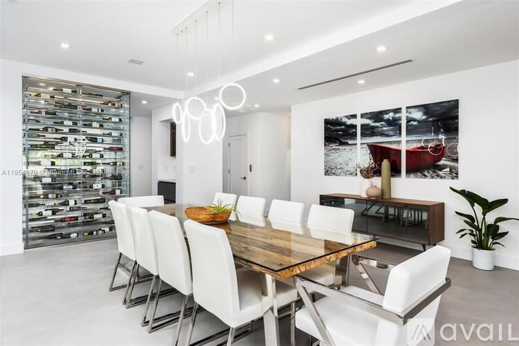 A modern dining room with a wooden table and white chairs.