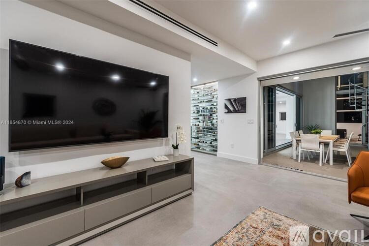 A modern living room with a large flat screen TV mounted on the wall.