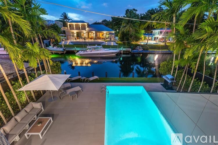 A swimming pool in a backyard with a patio and a house in the background.