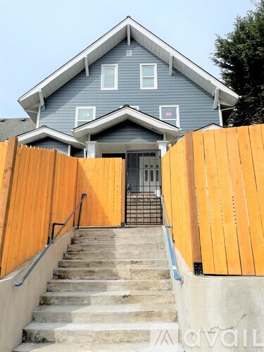 A blue house with a wooden fence and stairs leading to the front door.