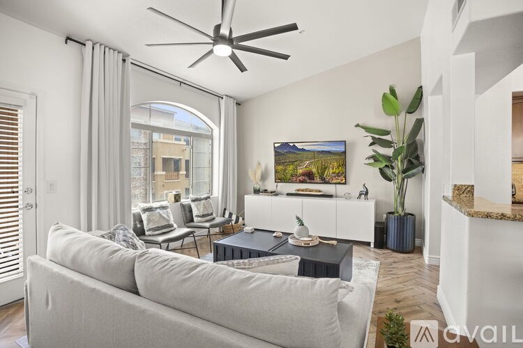 A living room with a grey couch and a ceiling fan.