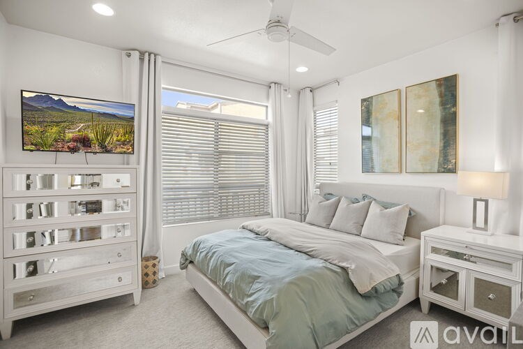 A bedroom with a bed, nightstand, and a television displaying a landscape.