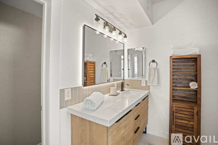 A bathroom with a vanity, mirror, and lights.