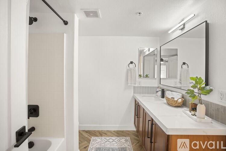 A bathroom with a white tub and sink, a mirror, and a plant.