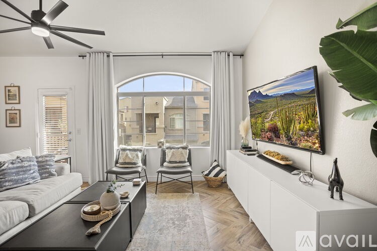 A living room with a large window, a flat screen TV, and a white sofa.