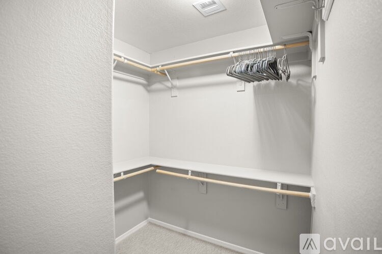 A white closet with a coat hanger and a coat hanging on it.