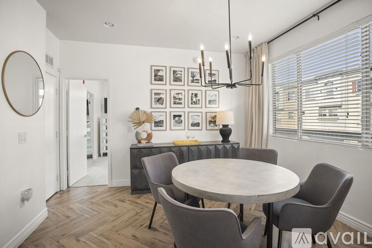 A dining room with a round table and grey chairs.